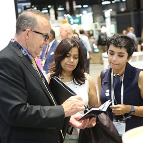 IFT FIRST exhibitor showing a booklet to two attendees on the bustling show floor