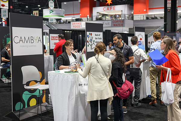 IFT FIRST attendees gathered in front of exhibitor booths talking excitedly to each other