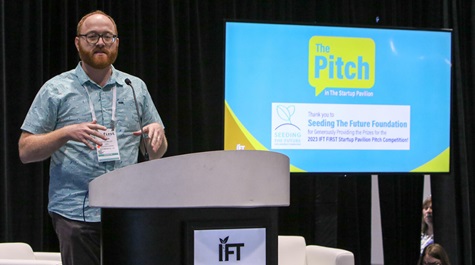 IFT FIRST The Pitch finale with startup presenting on stage at a podium with tv screen next to it