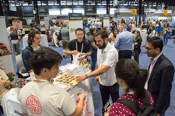 IFT FIRST Startup Pavilion people grabbing samples from a startup kiosk